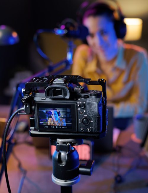 Young youtuber recording a video in her studio, professional camera in the foreground